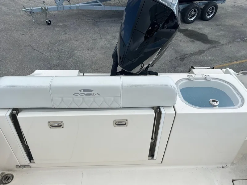 Slide: The Image of 2022 Cobia 237 Center Console boat with seating and motor, parked on pavement. - 5