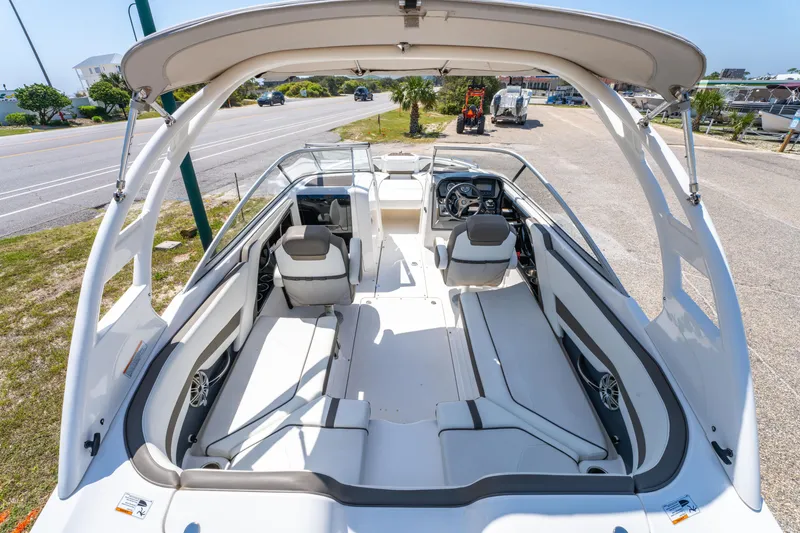Slide: The Image of 2015 Yamaha Boats 242 Limited S interior with seating and helm, parked on a sunny day. - 12