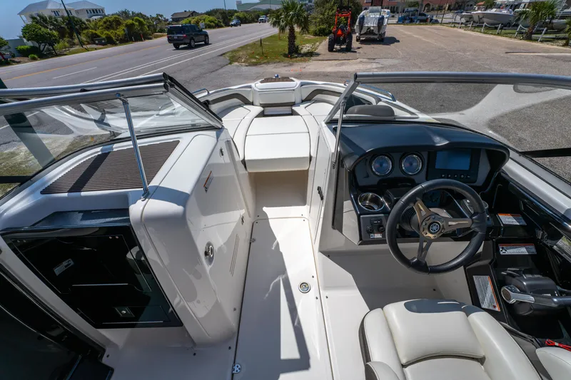 Slide: The Image of 2015 Yamaha Boats 242 Limited S interior with steering wheel and dashboard, parked near a road. - 13