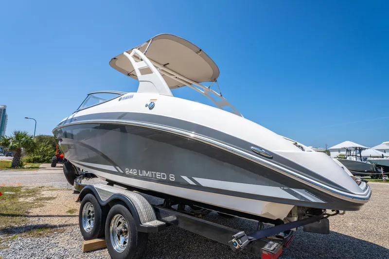 Slide: The Image of 2015 Yamaha Boats 242 Limited S on trailer, sleek design under clear blue sky. - 3