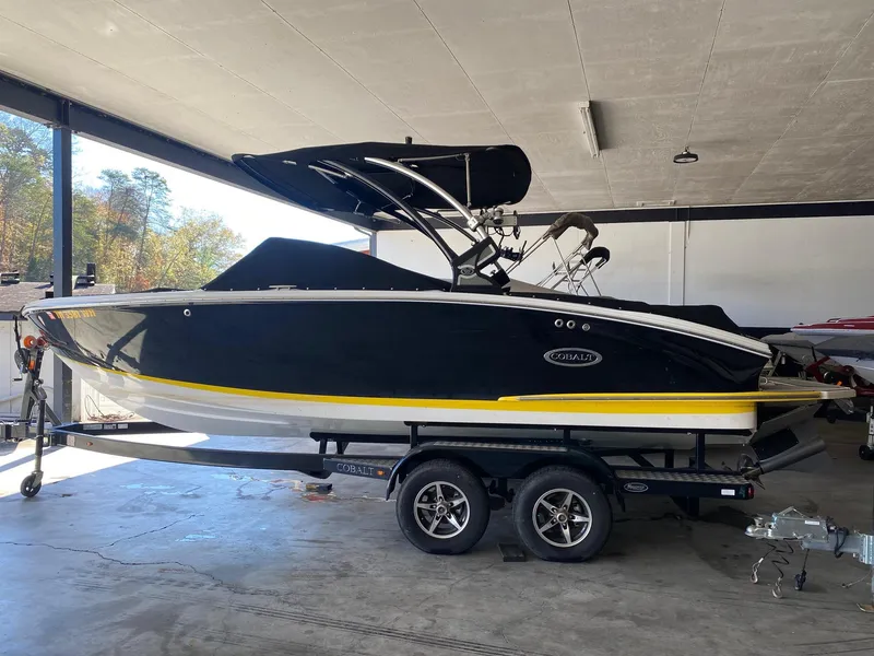 Slide: The Image of 2022 Cobalt CS23 Surf boat on trailer in a garage setting. - 2
