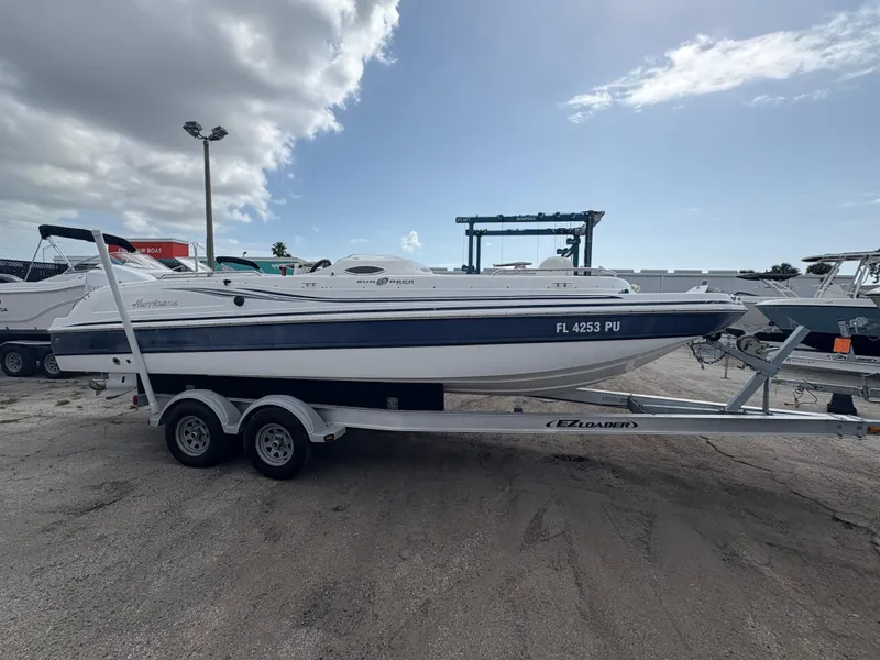 The Image of 2014 Hurricane SunDeck Sport 232 OB boat on trailer, parked outdoors under cloudy sky. - 0