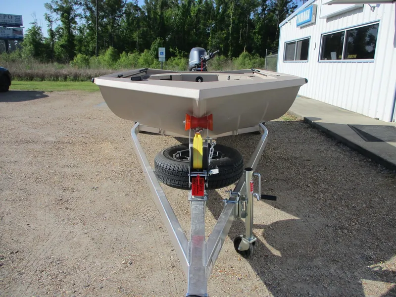 Slide: The Image of 2025 Avid 18 Commander boat on trailer, parked outdoors near a building. - 2