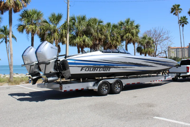 Slide: The Image of 2025 Fountain 34 Thundercat boat on trailer, parked near palm trees and ocean. - 14