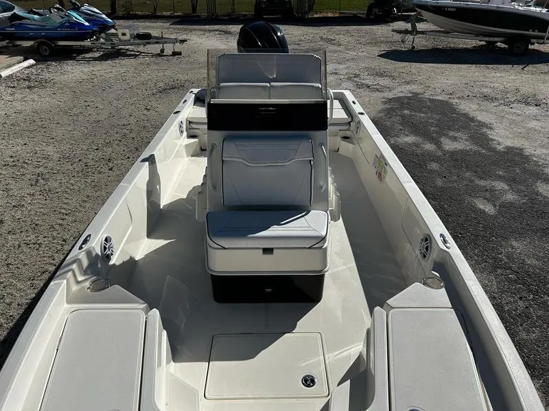 Slide: The Image of 2024 Skeeter SX230 boat interior with seating and console, parked on gravel. - 7