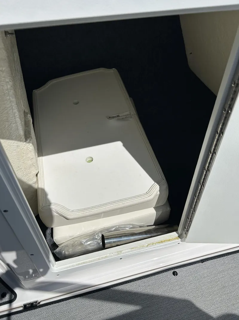 Slide: The Image of 2021 Yamaha Boats SX 210 storage compartment with white interior and closed hatch. - 10