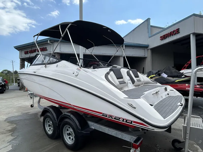 Slide: The Image of 2021 Yamaha Boats SX 210 on trailer, parked outside service center. - 2