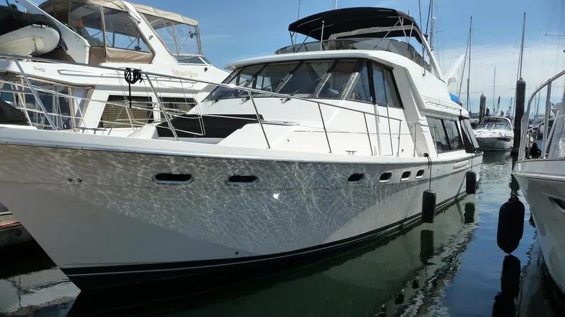 The Image of 1995 Bayliner 4788 Pilot House Motoryacht docked in a marina, reflecting on water. - 0