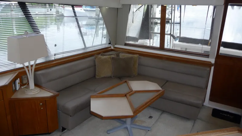 Slide: The Image of 1995 Bayliner 4788 Pilot House Motoryacht interior with gray seating and geometric table. - 13