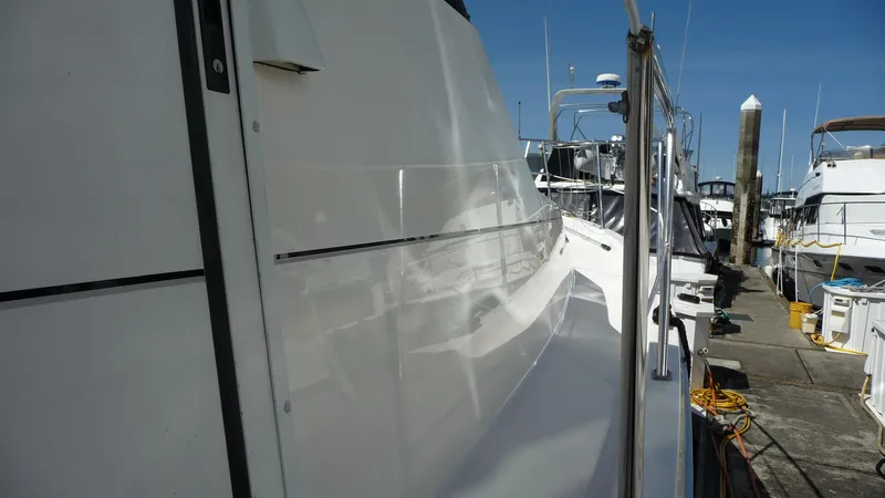 Slide: The Image of 1995 Bayliner 4788 Pilot House Motoryacht docked, showcasing sleek white exterior and marina setting. - 2
