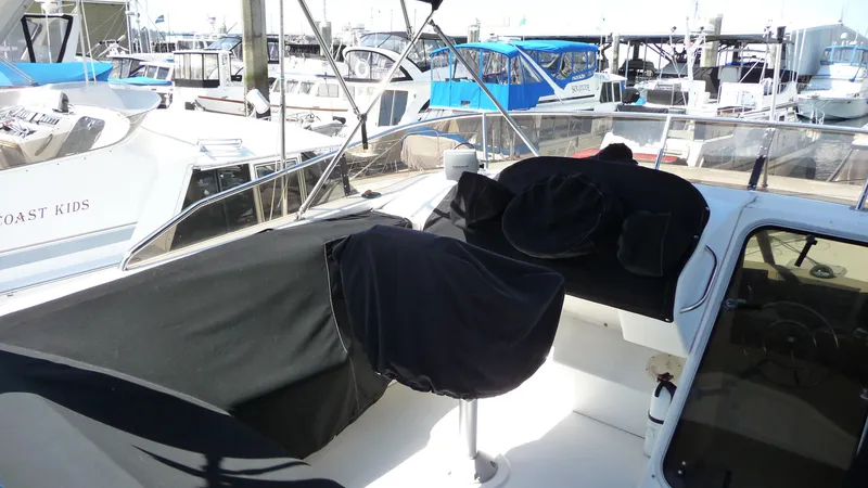 Slide: The Image of 1995 Bayliner 4788 Pilot House Motoryacht docked, featuring covered seating and helm area. - 48