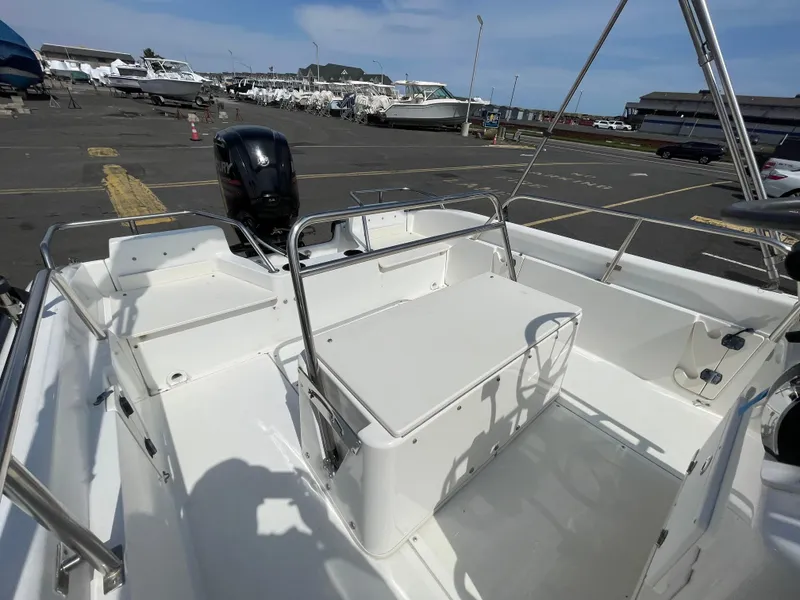 Slide: The Image of 1999 Boston Whaler 16 Dauntless boat interior with seating and steering wheel in a marina. - 14