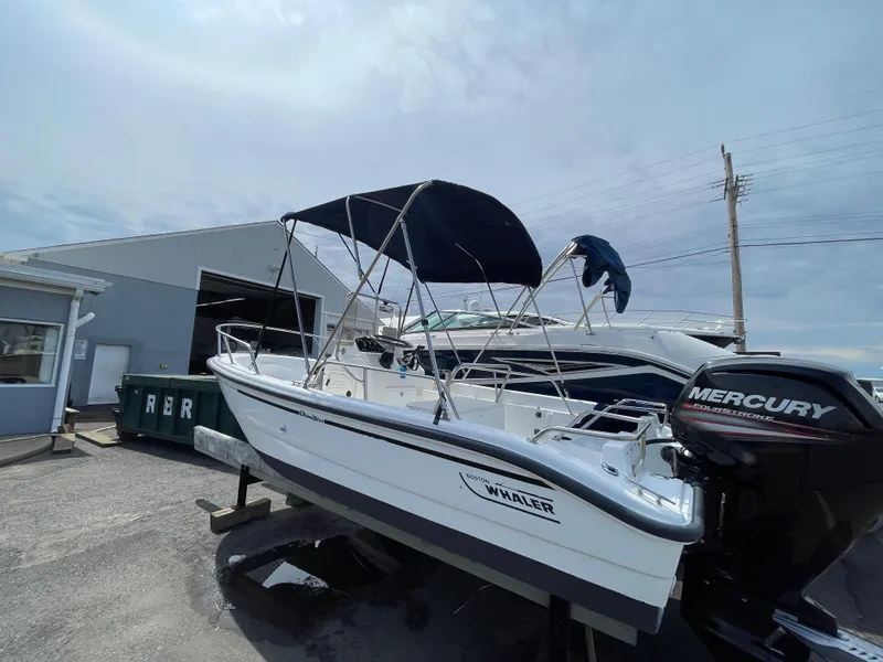 Slide: The Image of 1999 Boston Whaler 16 Dauntless boat with canopy and Mercury engine, parked outdoors. - 16