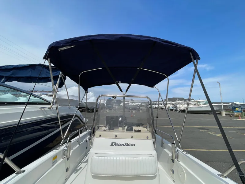Slide: The Image of 1999 Boston Whaler 16 Dauntless boat with blue canopy, docked in marina. - 17