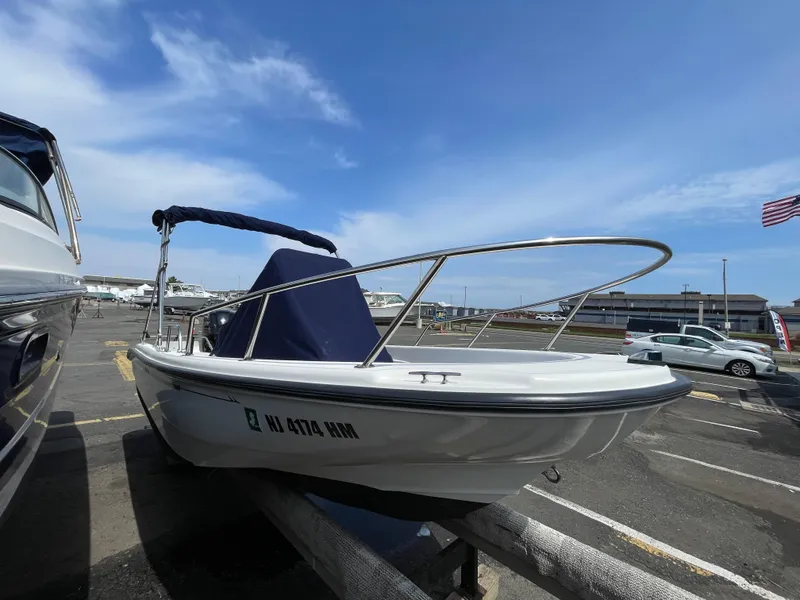 Slide: The Image of 1999 Boston Whaler 16 Dauntless boat on trailer in sunny marina. - 2