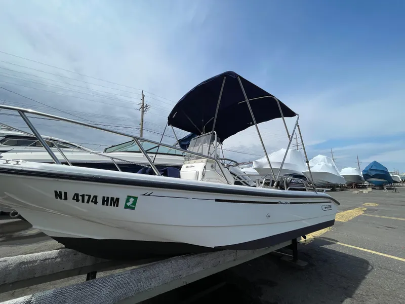 Slide: The Image of 1999 Boston Whaler 16 Dauntless boat with canopy, docked in a marina under a clear sky. - 20