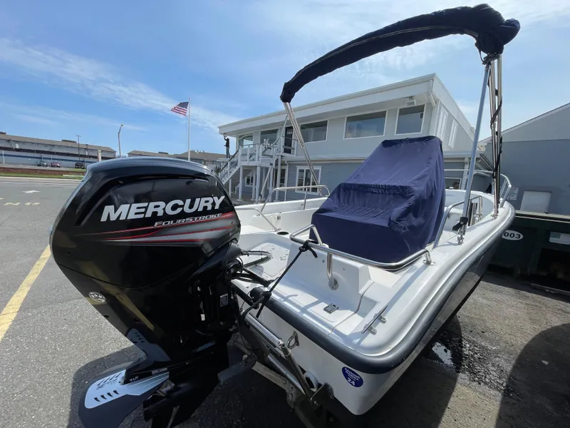 Slide: The Image of 1999 Boston Whaler 16 Dauntless boat with Mercury engine, docked near a building. - 4