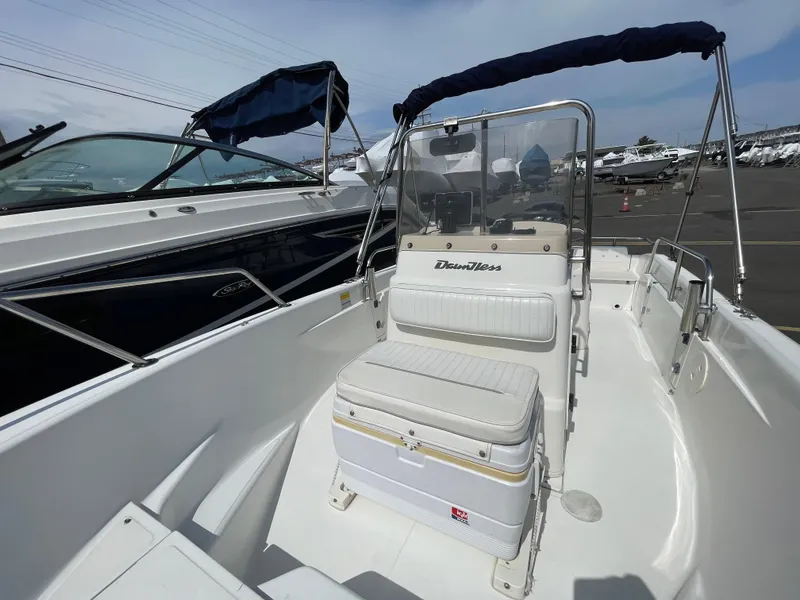 Slide: The Image of 1999 Boston Whaler 16 Dauntless boat interior with seating and console, docked outdoors. - 6