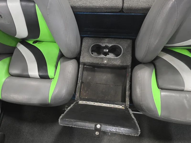 Slide: The Image of 2014 Bass Cat Eyra boat interior with green and gray seats, cup holders, and storage compartment. - 13