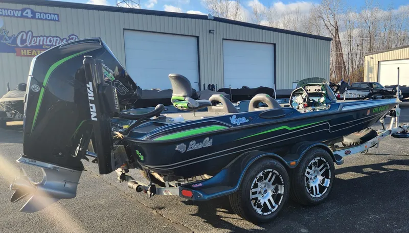 Slide: The Image of 2014 Bass Cat Eyra boat with dual axle trailer, parked outdoors near a warehouse. - 17
