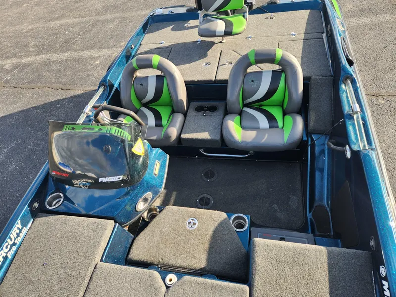 Slide: The Image of 2014 Bass Cat Eyra boat interior with green and gray seats, steering console, and storage compartments. - 24