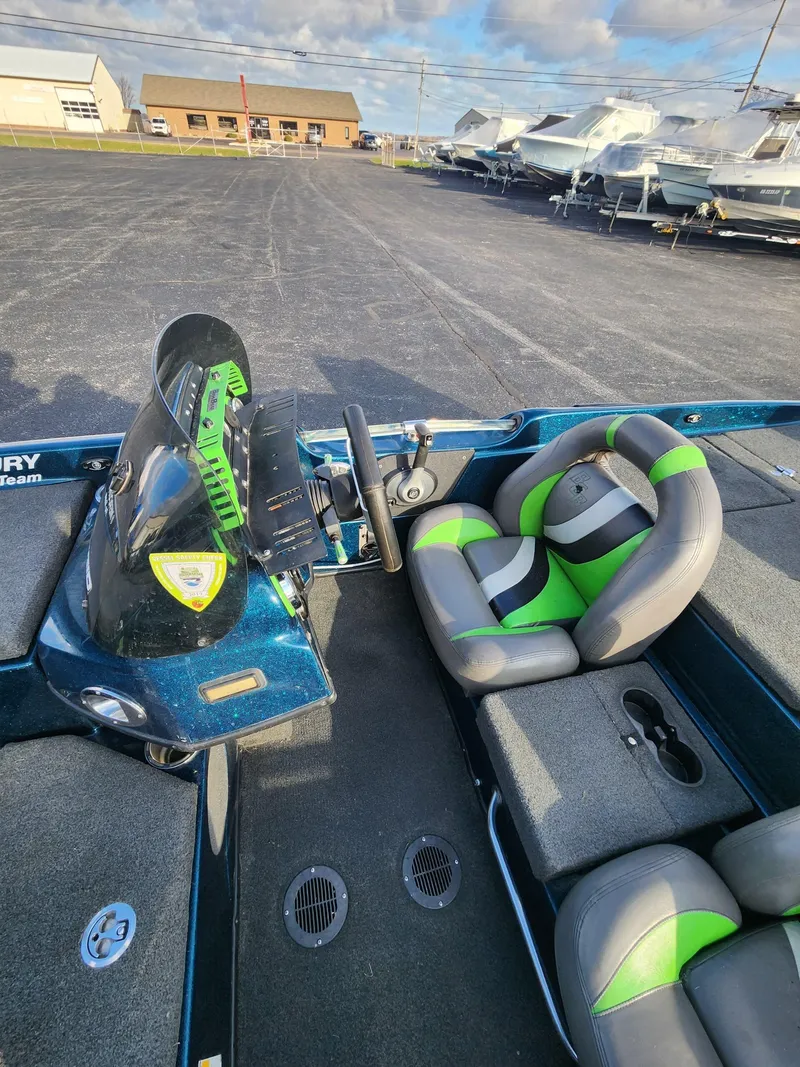 Slide: The Image of 2014 Bass Cat Eyra boat interior with green and gray seats, parked on asphalt. - 28