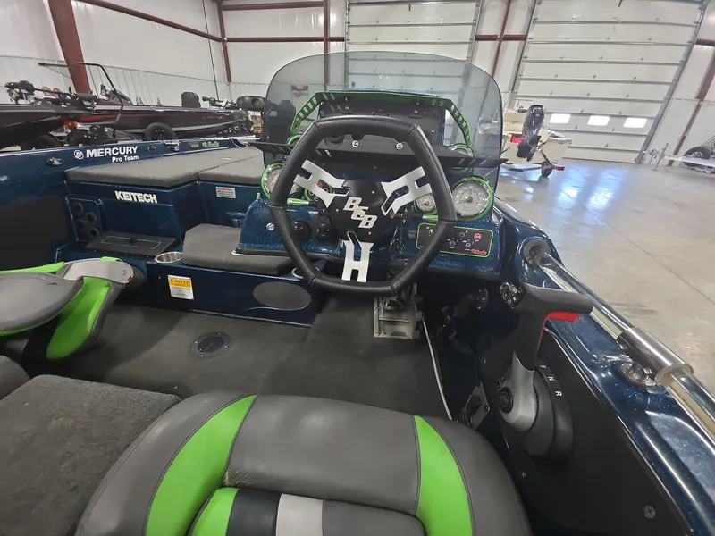 Slide: The Image of 2014 Bass Cat Eyra boat interior with steering wheel and dashboard in a garage setting. - 6