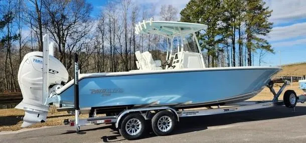 Slide: The Image of 2024 Pathfinder 2700 Open boat on trailer, parked outdoors with trees in background. - 2