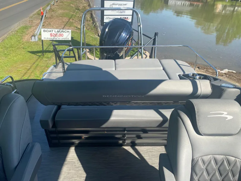Slide: The Image of 2022 Bennington LX 24 Swingback pontoon boat with plush seating near a lake. - 12