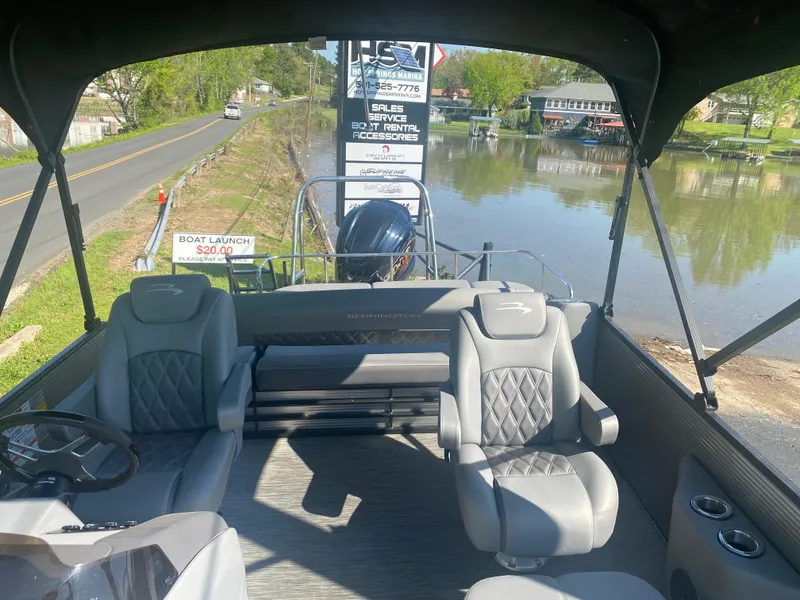 Slide: The Image of 2022 Bennington LX 24 Swingback pontoon boat interior with gray seating near a calm river. - 5