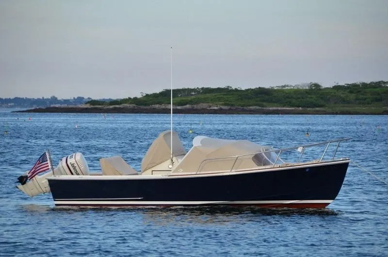 Slide: The Image of 1986 Padebco 21 boat on calm water, featuring classic design and American flag. - 1