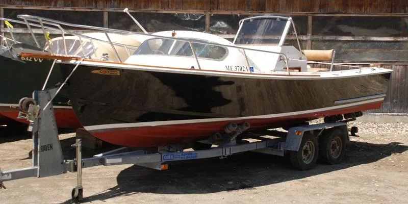 Slide: The Image of 1986 Padebco 21 boat on trailer, black hull, parked outdoors. - 2