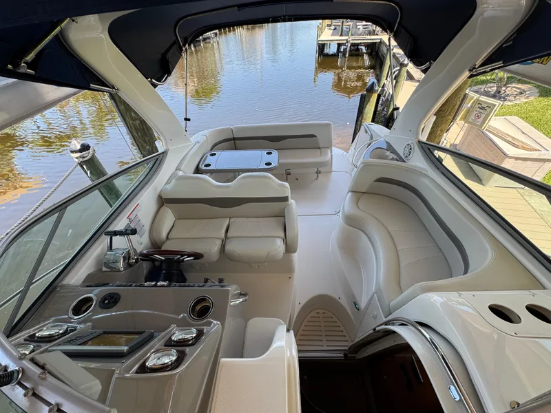 Slide: The Image of 2009 Chaparral Signature 290 boat interior with seating and control panel, docked by the water. - 12