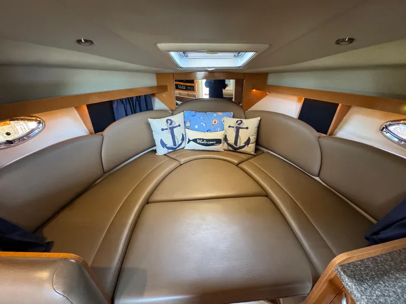 Slide: The Image of 2009 Chaparral Signature 290 cabin interior with cozy seating and nautical-themed pillows. - 22