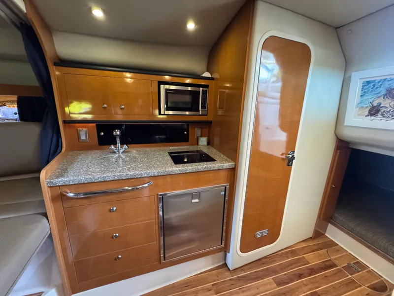 Slide: The Image of 2009 Chaparral Signature 290 interior with kitchenette, featuring wood cabinetry and modern appliances. - 23