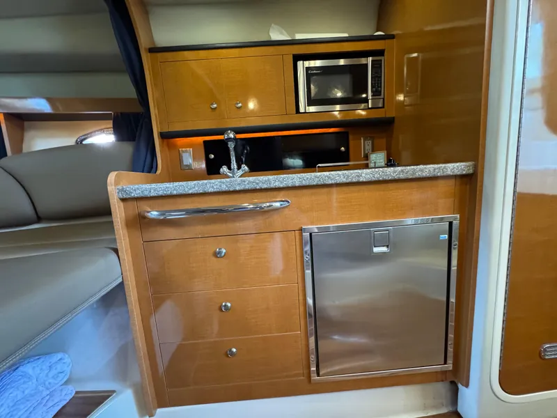 Slide: The Image of 2009 Chaparral Signature 290 interior kitchen with wood cabinetry, microwave, and stainless steel fridge. - 24