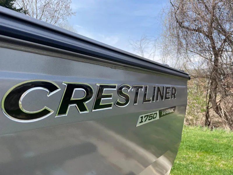 Slide: The Image of 2025 Crestliner 1750 Hawk SC boat side view with logo, outdoors. - 19