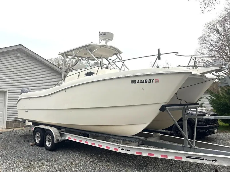 Slide: The Image of 2001 World Cat 266 SC boat on trailer, parked near a garage. - 0