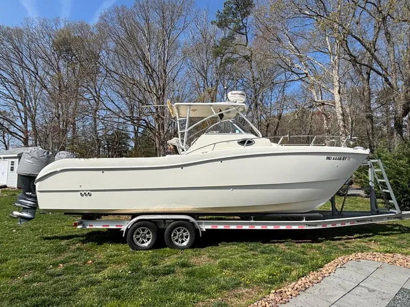 Slide: The Image of 2001 World Cat 266 SC boat on trailer, parked on grass with trees in background. - 1