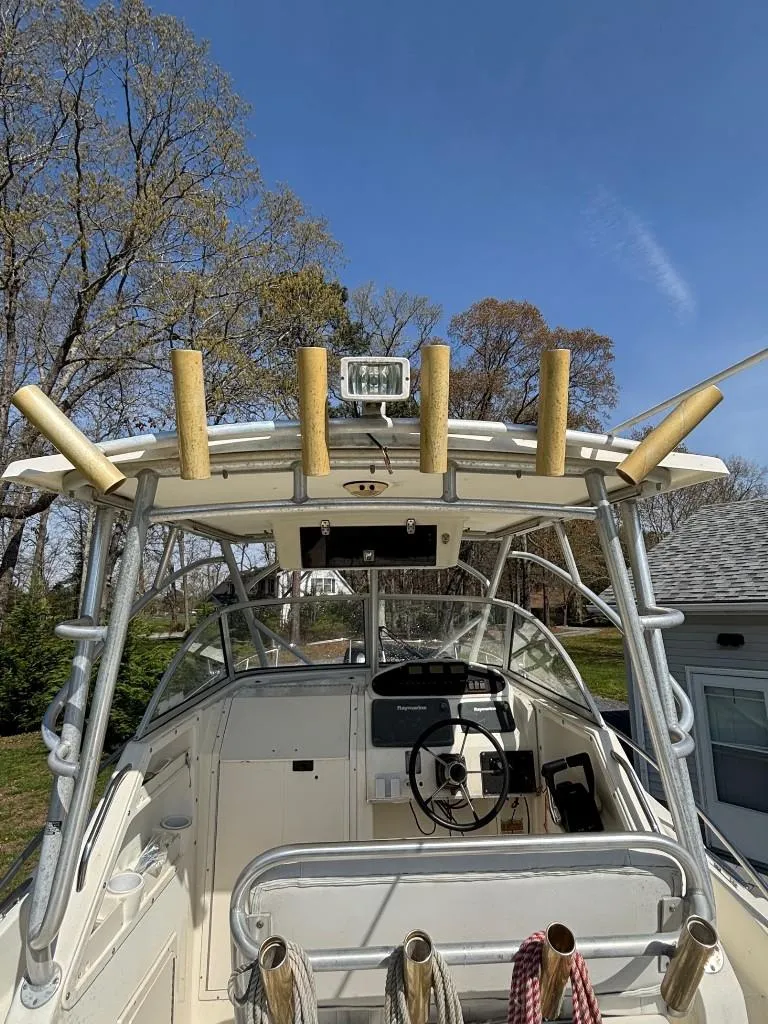 Slide: The Image of 2001 World Cat 266 SC boat with fishing rod holders and steering console, set outdoors. - 2