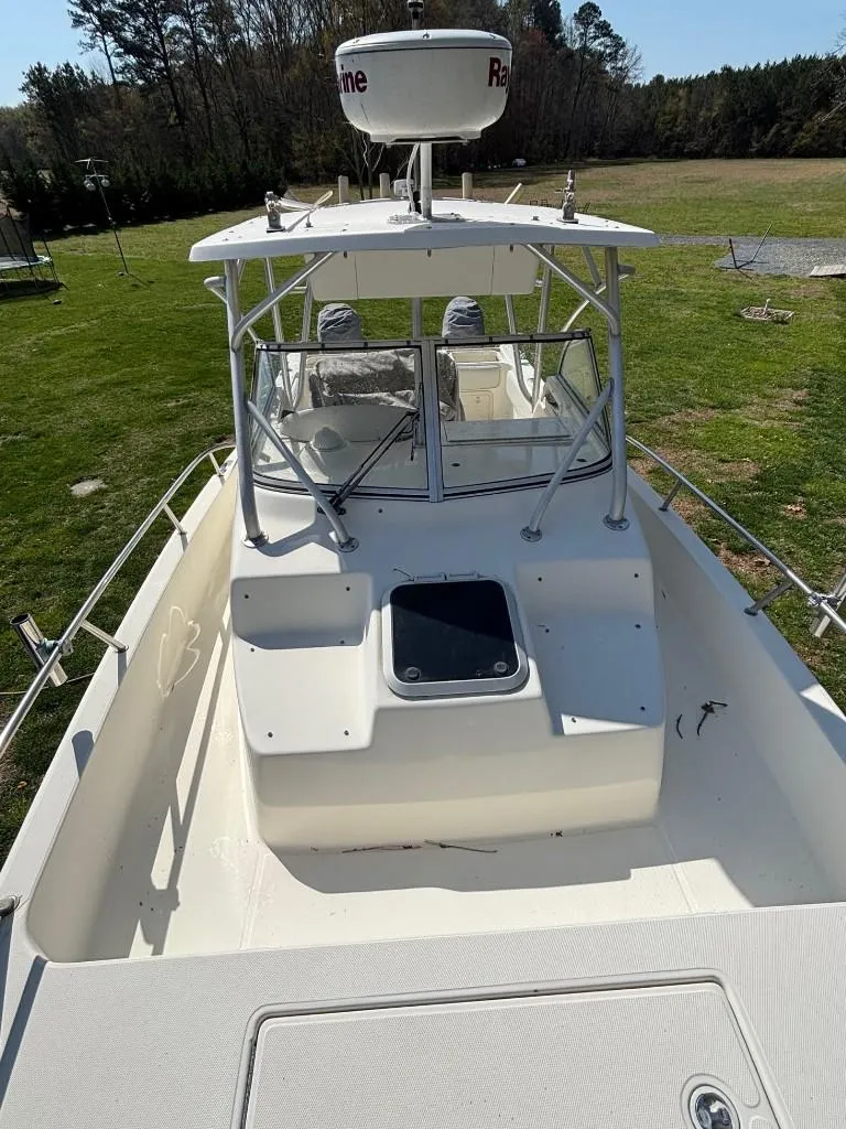 Slide: The Image of 2001 World Cat 266 SC boat on grass, featuring a spacious deck and radar equipment. - 7