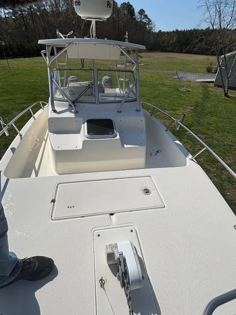 Slide: The Image of 2001 World Cat 266 SC boat on grassy area, showcasing deck and cabin. - 8