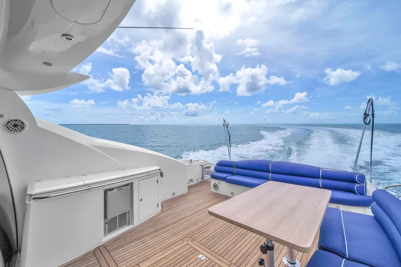 Slide: The Image of Sunseeker Predator 72 yacht deck with ocean view, featuring blue seating and wooden table. - 24