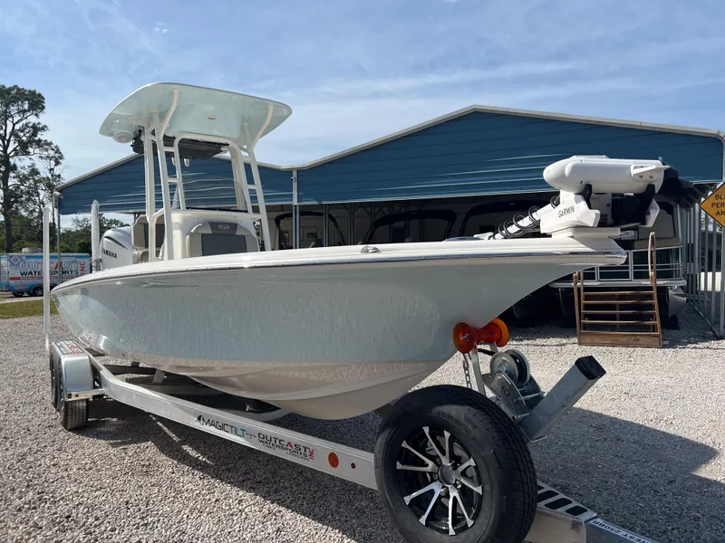 Slide: The Image of 2025 Key West 250 Bay Reef boat on trailer, parked outdoors near a blue building. - 6