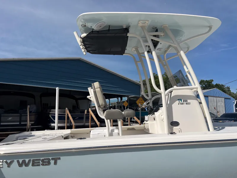 Slide: The Image of 2025 Key West 250 Bay Reef boat with T-top and seating, docked near blue building. - 8