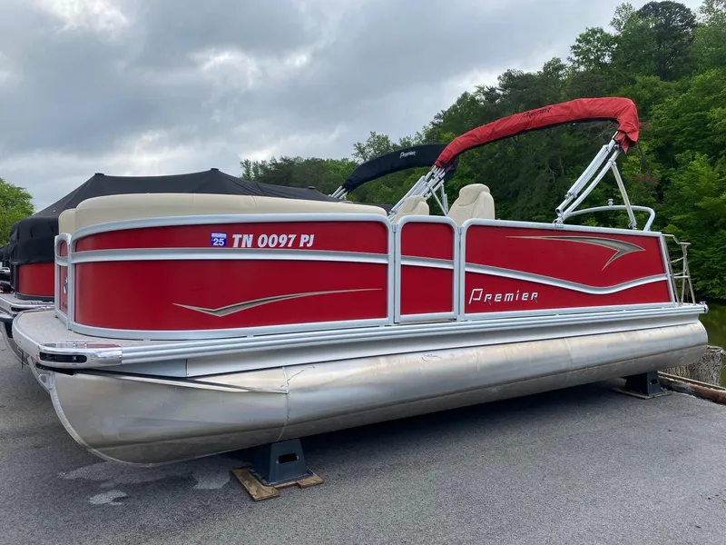 The Image of 2022 Premier 210 Sunsation RL pontoon boat with red exterior, docked on a cloudy day. - 1