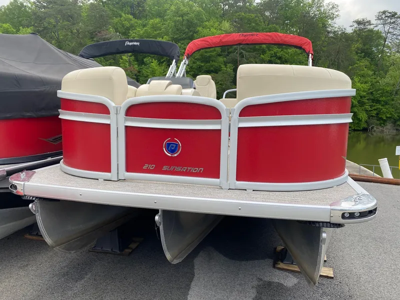 Slide: The Image of 2022 Premier 210 Sunsation RL pontoon boat with red and white design, docked outdoors. - 6