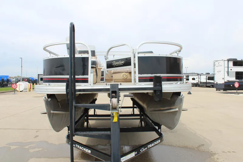 Slide: The Image of 2014 Sun Tracker Bass Buggy 18 DLX pontoon boat on trailer, parked outdoors. - 2