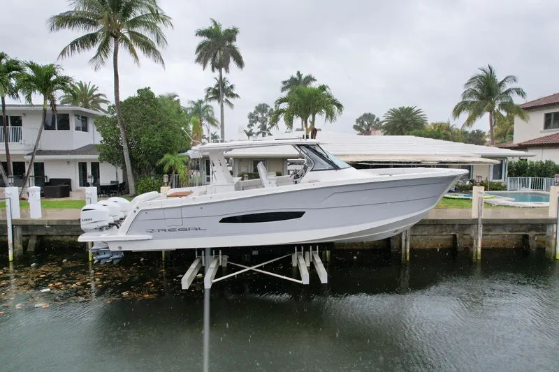 Slide: The Image of 2021 Regal 38 SAV boat docked near waterfront homes with palm trees. - 1