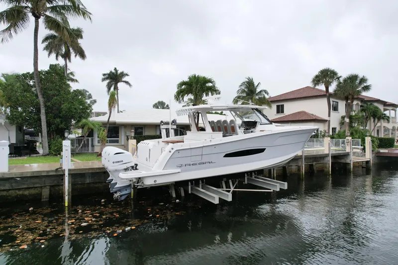 Slide: The Image of 2021 Regal 38 SAV boat docked by waterfront homes with palm trees. - 2